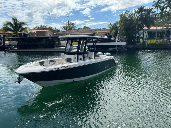  Yacht Photos Pics 2022 Robalo R272 boat on calm water with palm trees in the background.