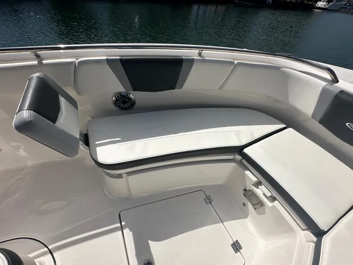  Yacht Photos Pics 2022 Robalo R272 boat interior with cushioned seating and storage, docked by the water.
