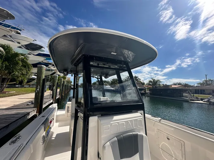  Yacht Photos Pics 2022 Robalo R272 boat docked by a canal under a clear blue sky.