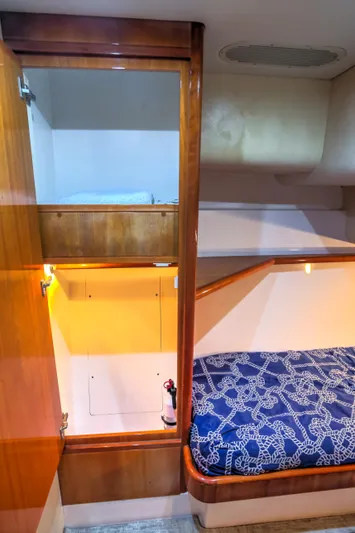  Yacht Photos Pics 2005 Bertram 450 Convertible cabin interior with wooden finish and blue patterned bedding.