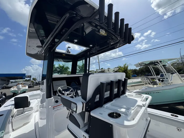  Yacht Photos Pics 2026 Blackfin 262 HB boat interior with steering console and rod holders under a sunny sky.