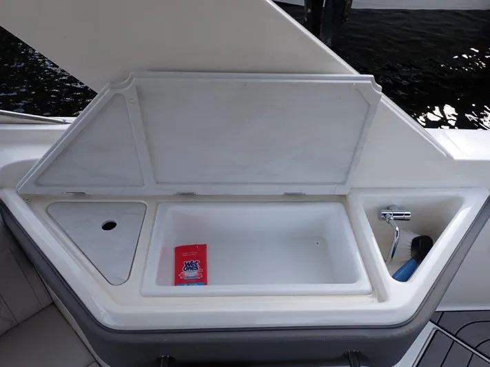  Yacht Photos Pics 2024 Sea Ray SLX 310 OB boat cooler compartment with open lid and cleaning supplies.