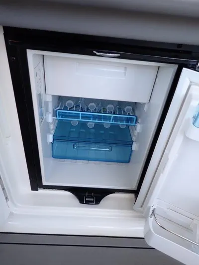  Yacht Photos Pics 2024 Sea Ray SLX 310 OB boat refrigerator with open door, showcasing interior storage.