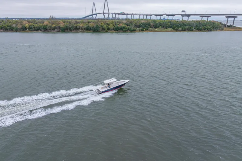  Yacht Photos Pics 2008 Jupiter 31 FS boat cruising on a river near a bridge and lush shoreline.