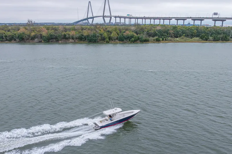  Yacht Photos Pics 2008 Jupiter 31 FS boat cruising on river with bridge and trees in background.