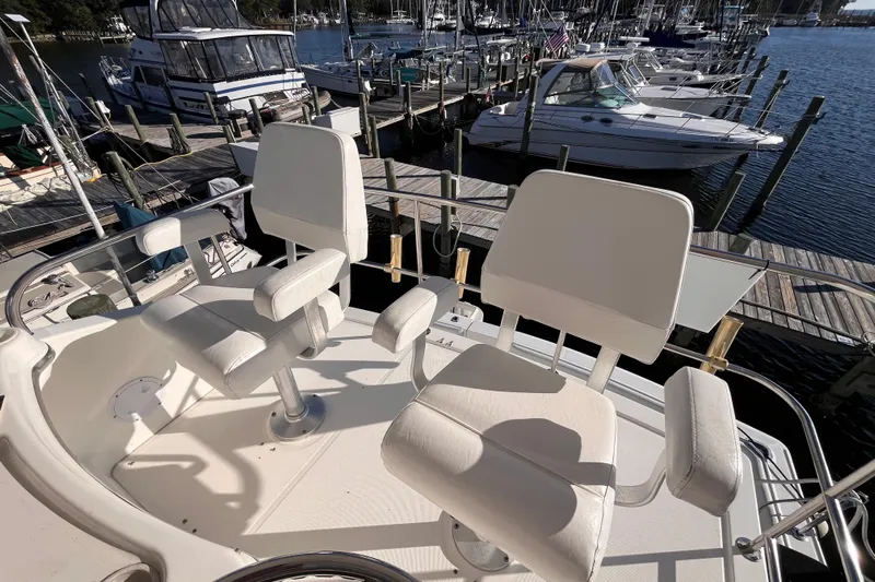  Yacht Photos Pics Two white captain chairs on a 2001 Silverton 42C yacht at a marina.