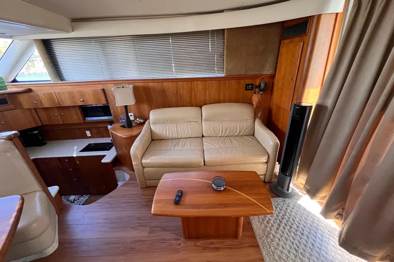  Yacht Photos Pics Interior of 2001 Silverton 42C yacht with beige sofa, wooden table, and kitchenette.