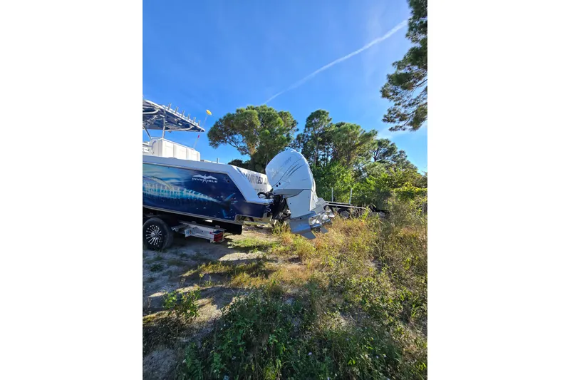  Yacht Photos Pics 2013 Invincible 42 Open Fisherman boat with outboard motor, parked on grassy terrain.
