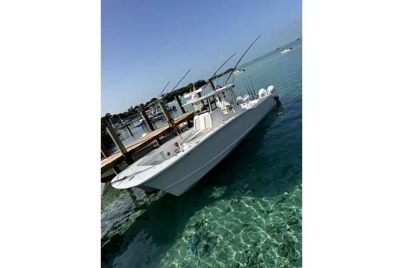  Yacht Photos Pics 2024 Tideline 365 boat docked in clear turquoise water, showcasing sleek design and fishing rods.