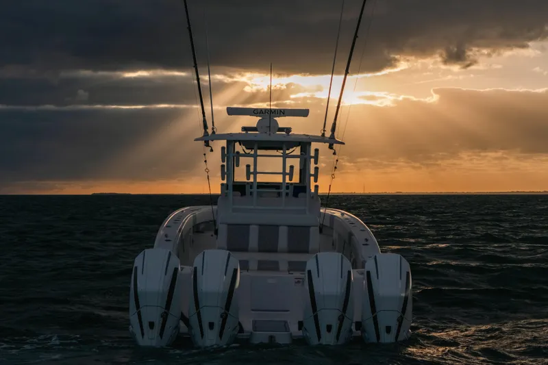  Yacht Photos Pics 2024 Tideline 365 boat at sunset on the ocean, featuring multiple outboard engines.