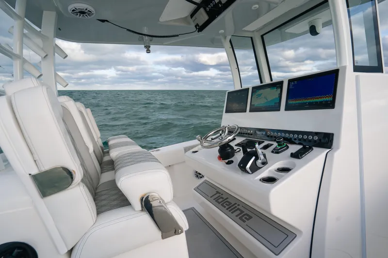  Yacht Photos Pics 2024 Tideline 365 boat cockpit with advanced navigation screens and plush seating on open water.