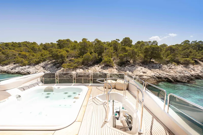 Koukles Yacht Photos Pics Luxurious 2008 Azimut 95 E yacht deck with jacuzzi, overlooking serene coastal landscape.