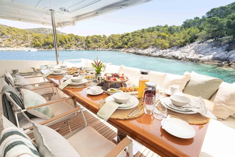 Koukles Yacht Photos Pics Luxurious dining setup on 2008 Azimut 95 E yacht, overlooking serene coastal waters.
