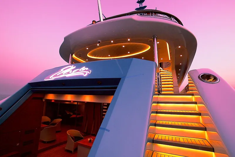Elada Yacht Photos Pics Luxurious Bilgin 147 yacht with illuminated stairs against a vibrant pink sunset sky.