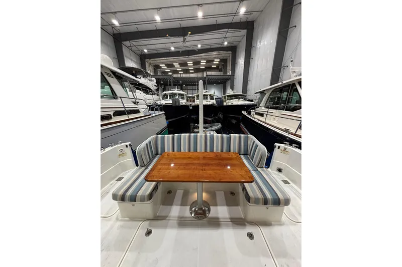 Cellibrate Yacht Photos Pics 2020 Sabre 45 Salon Express yacht interior with striped seating and wooden table in a marina.