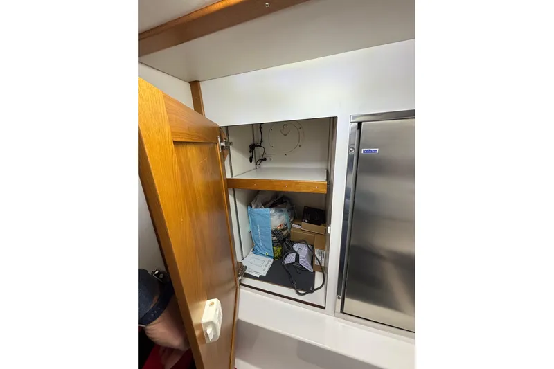 Cellibrate Yacht Photos Pics Open wooden cabinet on 2020 Sabre 45 Salon Express yacht, revealing storage items.