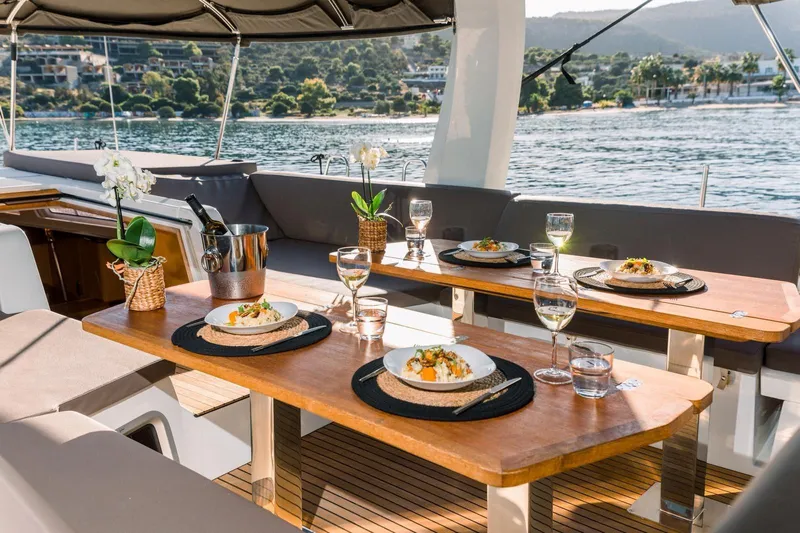 Euphoria Yacht Photos Pics Luxurious dining setup on 2021 Jeanneau 60 yacht, overlooking serene waters.