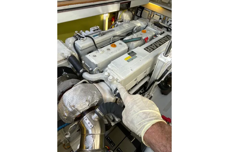 Skylark Yacht Photos Pics Engine of 2005 Lyman-Morse Monhegan boat with Yanmar branding, inspected by gloved hand.