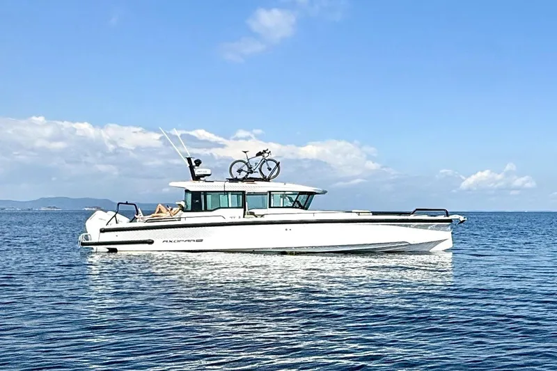  Yacht Photos Pics 2025 Axopar 37 XC CROSS CABIN boat on calm sea with bicycle on roof.