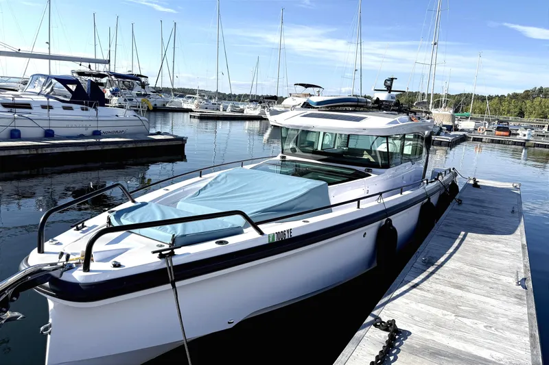  Yacht Photos Pics 2025 Axopar 37 XC CROSS CABIN docked at a marina, surrounded by sailboats.