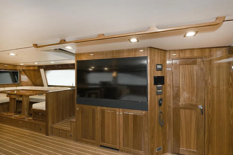 On The Edge Yacht Photos Pics Luxurious interior of 2018 Viking 80 Enclosed Skybridge yacht with wood paneling and large TV.