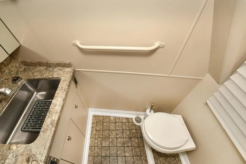 On The Edge Yacht Photos Pics Compact bathroom in 2018 Viking 80 Enclosed Skybridge with sink, toilet, and grab bar.