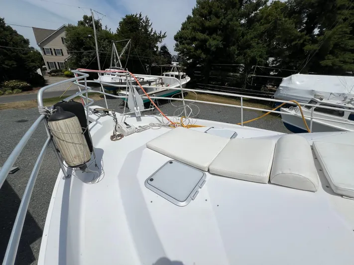 Amities Yacht Photos Pics 1998 Mainship 47 Motor Yacht deck with seating and railing, surrounded by trees and other boats.