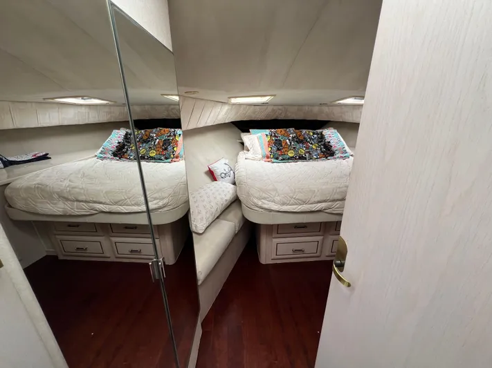 Amities Yacht Photos Pics 1998 Mainship 47 Motor Yacht bedroom with cozy bed, colorful pillows, and wooden flooring.