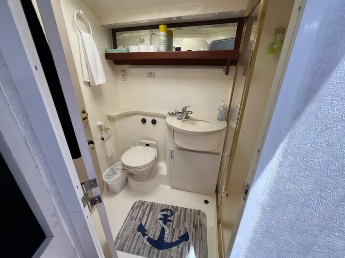 Amities Yacht Photos Pics Bathroom interior of 1998 Mainship 47 Motor Yacht with toilet, sink, and nautical-themed mat.