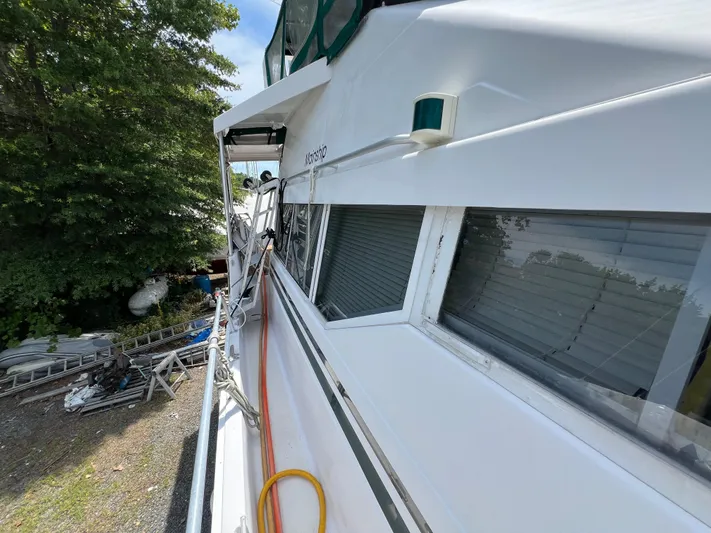 Amities Yacht Photos Pics 1998 Mainship 47 Motor Yacht side view with trees and equipment in the background.