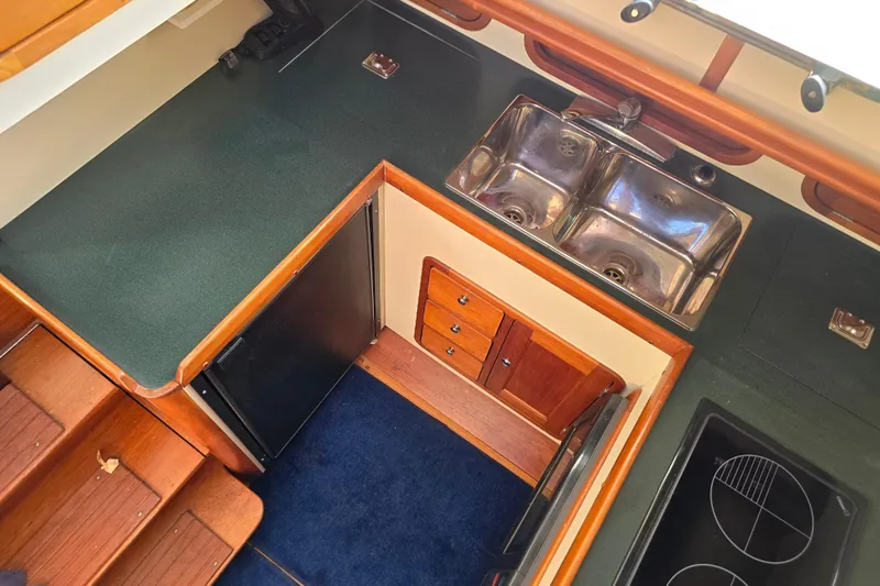 Lindy Yacht Photos Pics 2004 Legacy Yachts Sedan Flybridge kitchen with sink, stove, and wooden cabinetry.