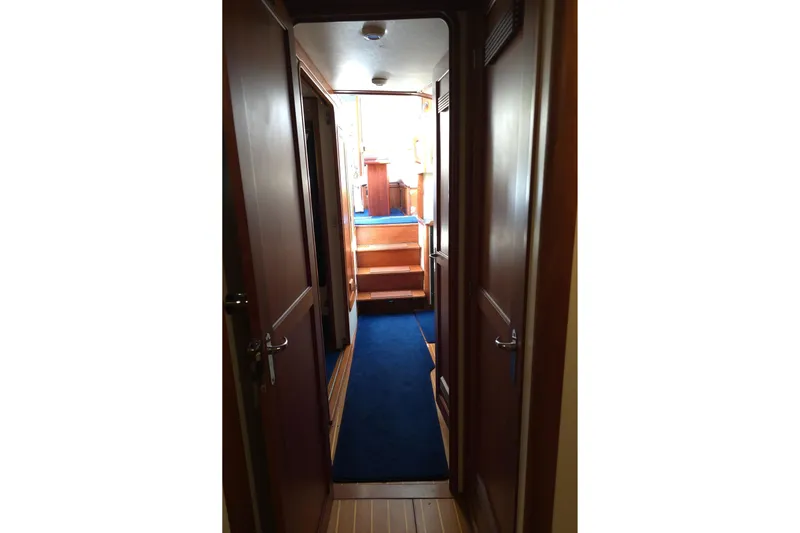 Lindy Yacht Photos Pics Interior hallway of 2004 Legacy Yachts Sedan Flybridge with blue carpet and wooden doors.
