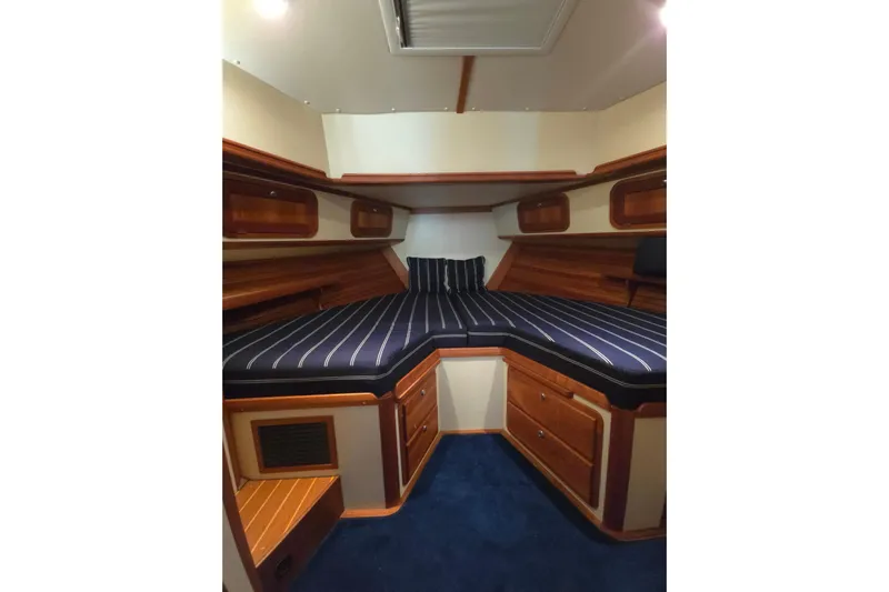 Lindy Yacht Photos Pics Luxurious 2004 Legacy Yachts Sedan Flybridge cabin with striped bedding and wooden accents.