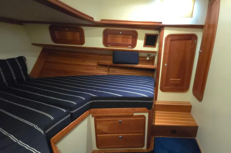 Lindy Yacht Photos Pics 2004 Legacy Yachts Sedan Flybridge cabin with striped bedding and wooden interior.