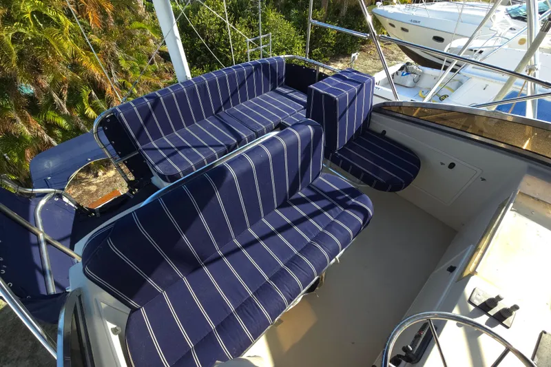 Lindy Yacht Photos Pics 2004 Legacy Yachts Sedan Flybridge with striped seating, docked near lush greenery.