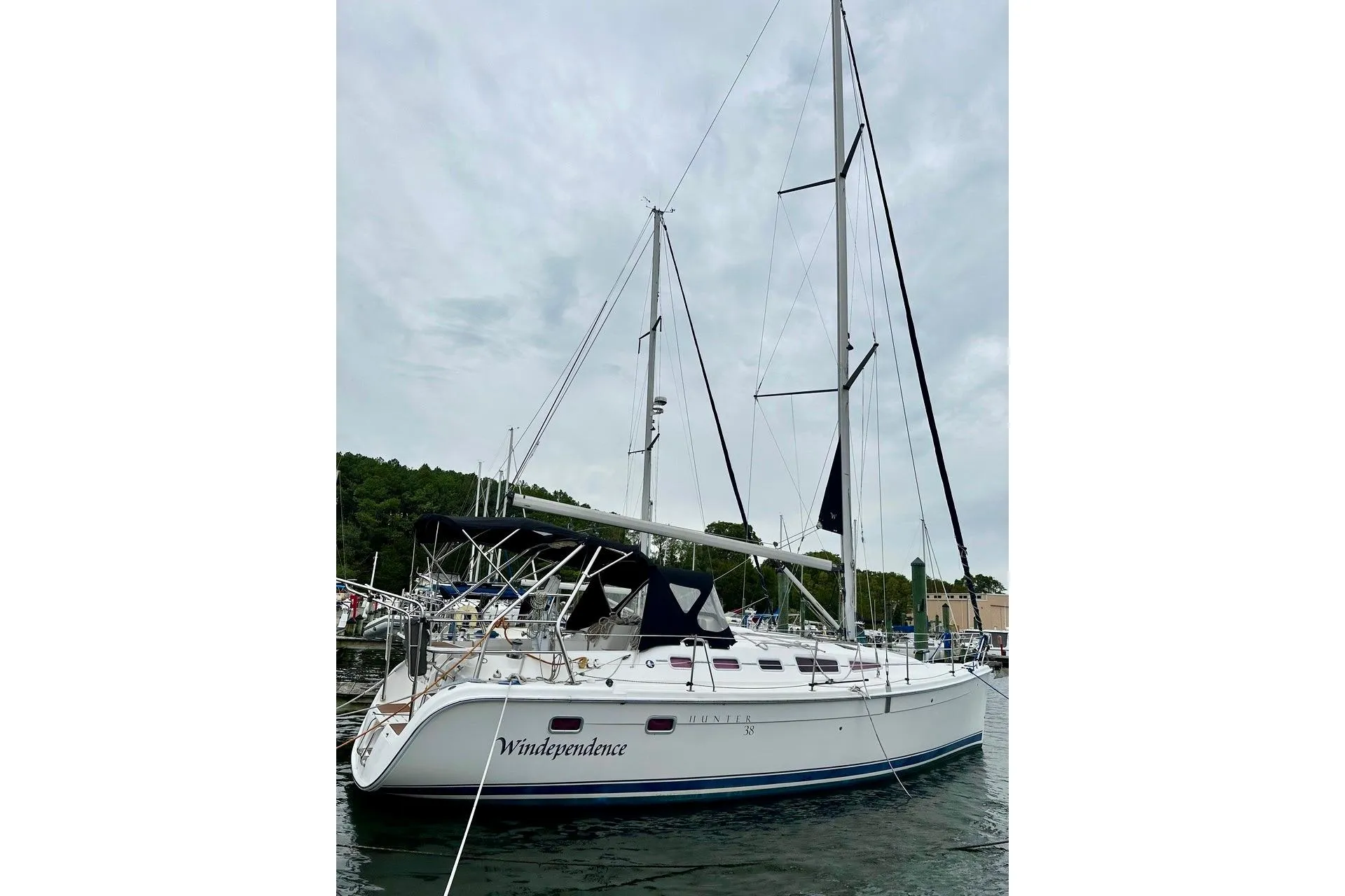 2006 Hunter 38 sailboat docked, featuring sleek design and tall mast against cloudy sky.