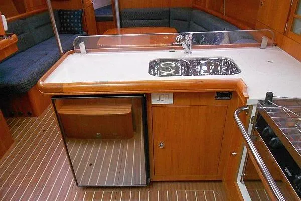 Windependence Yacht Photos Pics 2006 Hunter 38 yacht interior with kitchenette, featuring sink, fridge, and seating area.