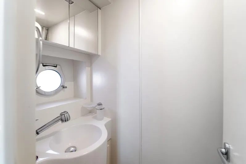 Giulia Yacht Photos Pics Modern bathroom interior on 2023 Ferretti Yachts 670, featuring sleek white design and round porthole window.