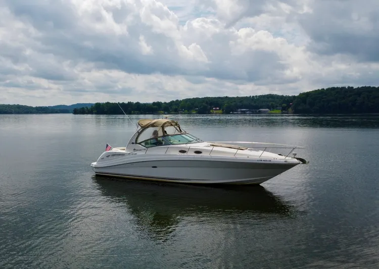  Yacht Photos Pics 2003 Sea Ray 340 Sundancer yacht on a calm lake under a cloudy sky.