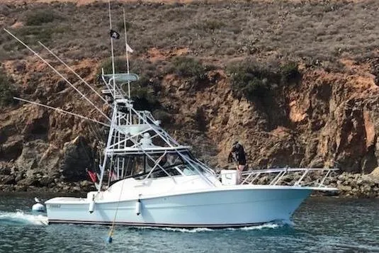 Beer Money Yacht Photos Pics 2004 Topaz 32 Express boat near rocky shoreline, featuring fishing equipment.