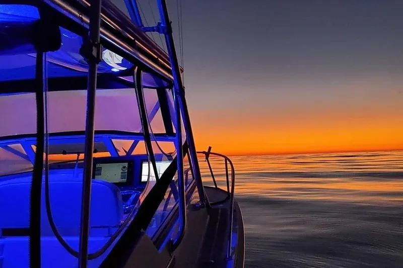 Beer Money Yacht Photos Pics 2004 Topaz 32 Express boat at sunset, vibrant orange sky reflecting on calm water.