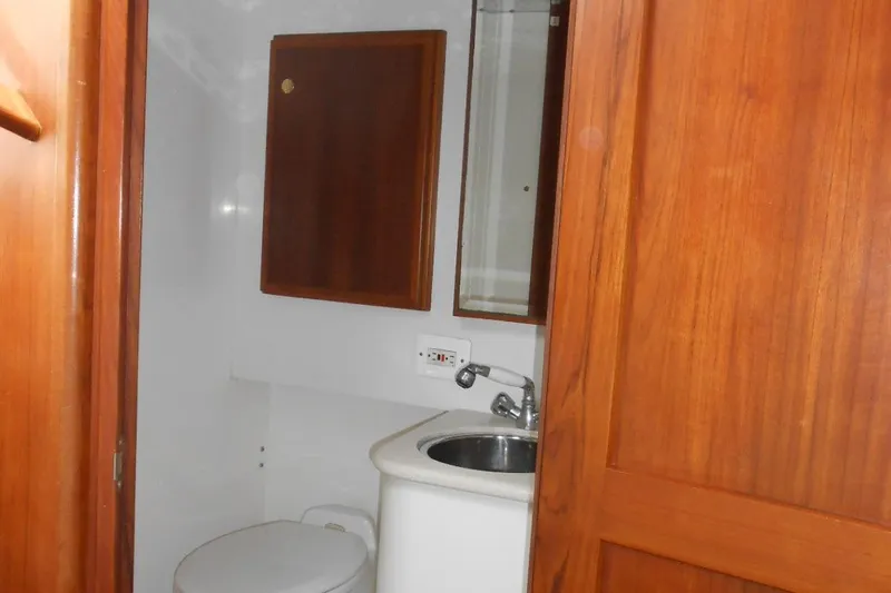Beer Money Yacht Photos Pics 2004 Topaz 32 Express boat bathroom with wooden cabinetry and compact sink.