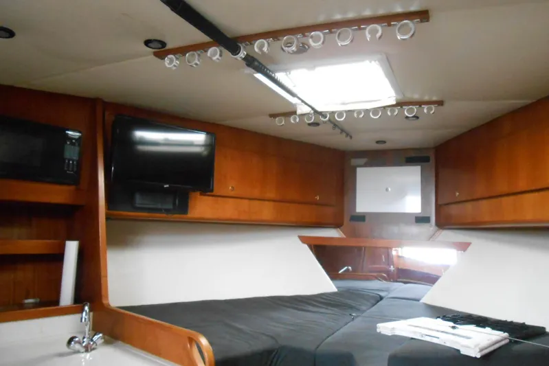 Beer Money Yacht Photos Pics Interior of 2004 Topaz 32 Express boat with bed, TV, and wooden cabinets.