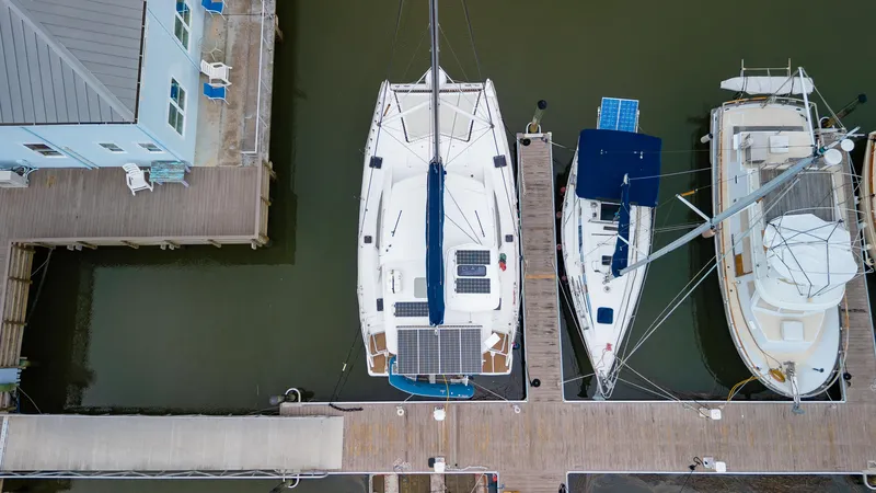 Papillon Yacht Photos Pics Aerial view of a 2012 Leopard 39 catamaran docked between two boats.