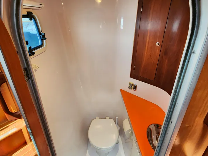 Frolic Yacht Photos Pics Compact bathroom in a 2014 Antares 44i yacht with wooden cabinetry and orange countertop.