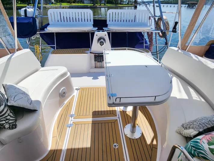 Frolic Yacht Photos Pics 2014 Antares 44i yacht cockpit with seating, table, and teak flooring on a sunny day.
