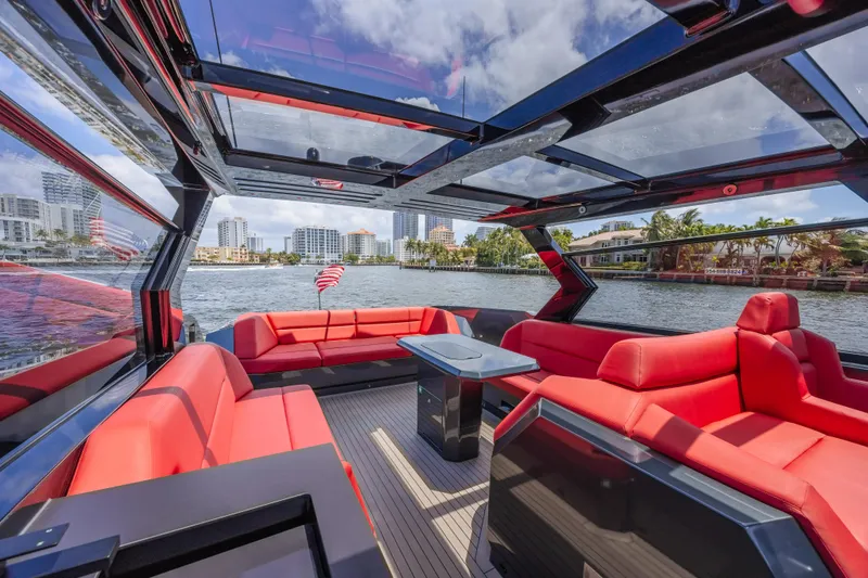 Moonshot Yacht Photos Pics Luxurious 2023 Vanquish Yachts VQ58 with red seating, glass roof, and waterfront city view.