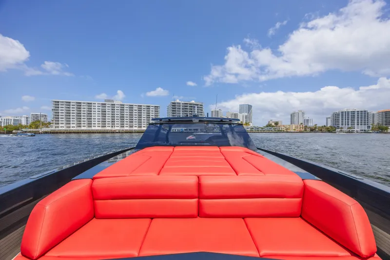 Moonshot Yacht Photos Pics 2023 Vanquish Yachts VQ58 with red seating, cruising near city skyline under blue sky.