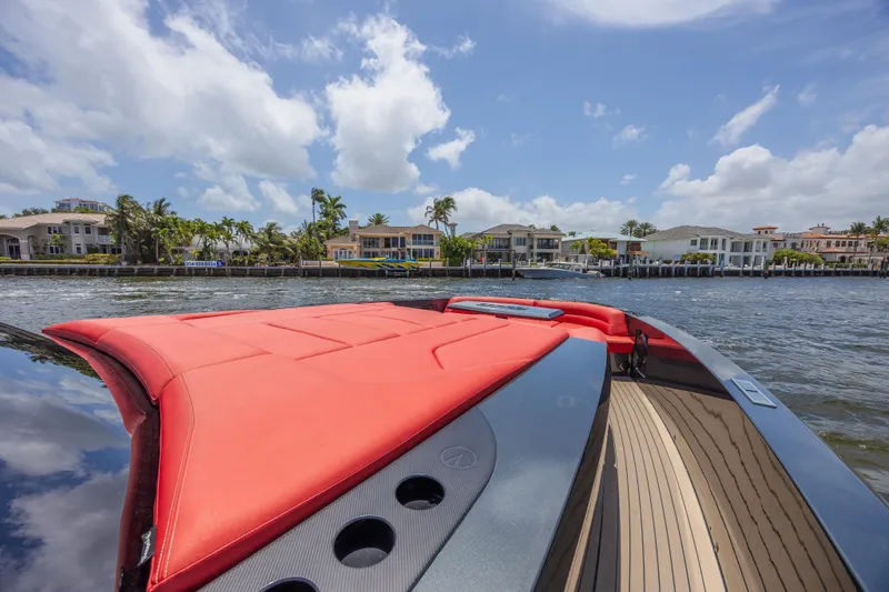 Moonshot Yacht Photos Pics 2023 Vanquish Yachts VQ58 with red seating, cruising near waterfront homes under a blue sky.