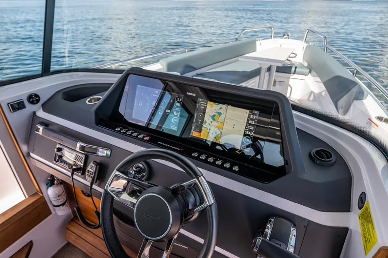 Windermere Yacht Photos Pics 2022 Axopar 28 boat dashboard with navigation display and steering wheel on open water.